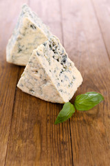 Tasty blue cheese with basil, on wooden table