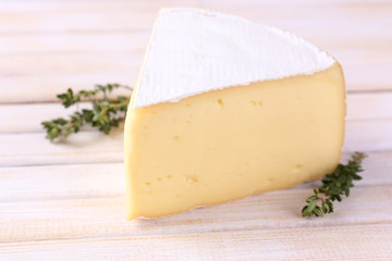 Tasty Camembert cheese with thyme, on wooden table