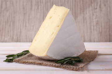 Tasty Camembert cheese with rosemary, on wooden table