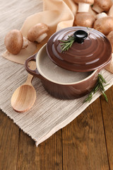 Mushroom soup in pot, on wooden background