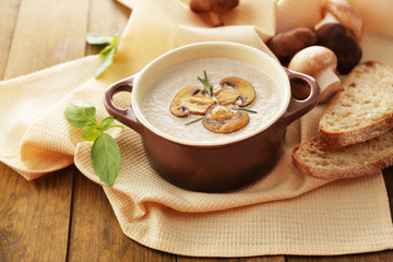 Mushroom soup in pot, on wooden background