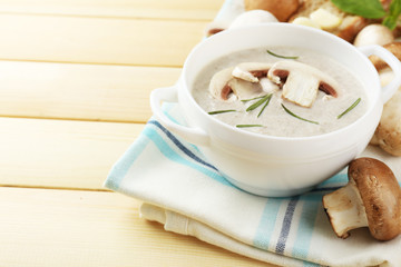 Mushroom soup in pot, on color napkin,  on wooden background