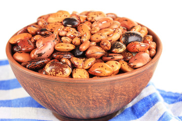 Raw beans in bowl on color napkin, isolated on white
