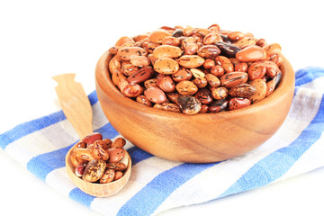 Raw beans in bowl on color napkin, isolated on white