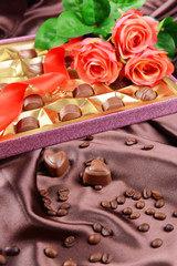 Delicious chocolates in box with flowers on brown background