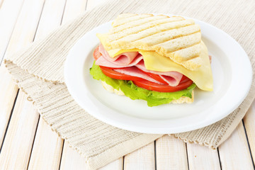 Tasty sandwich with ham on wooden table