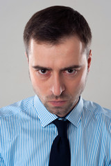 Angry emotion on face of business man isolated on grey backgroun