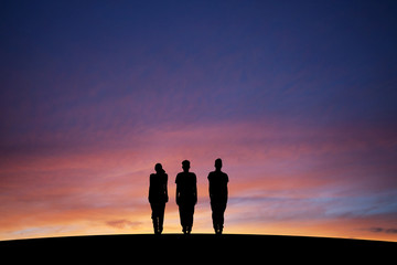 silhouetted three teenagers standing straight in sunset - 61334211