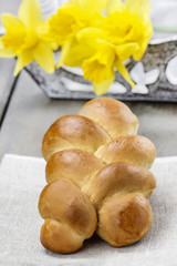 Easter bun and bouquet of daffodils in the background