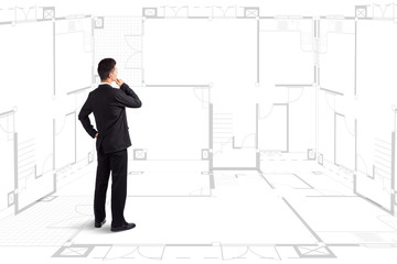Businessman standing near a house blueprints