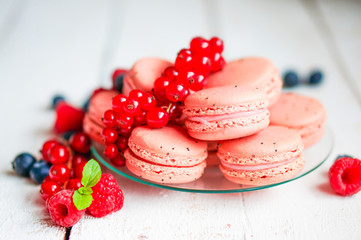 Raspberry macaroons with berries on wooden table