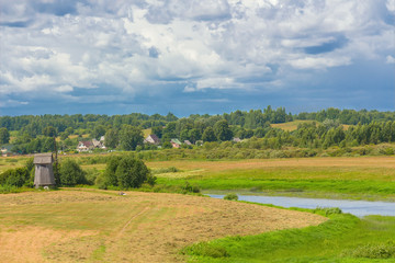 Fototapeta na wymiar Summer landscape with a field, the river and a windmill