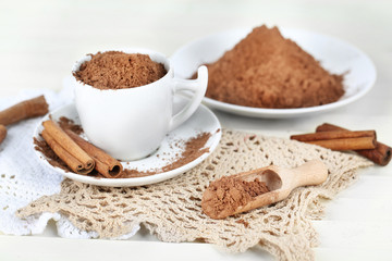 Fototapeta na wymiar Cocoa powder in cup on napkin on light background
