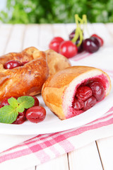 Fresh baked pasties with cherry on plate on table close-up