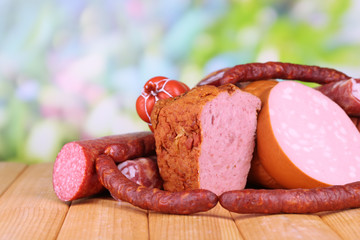 Lot of different sausages on wooden table on natural background