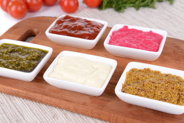 Various sauces on chopping board on table close-up