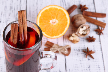 Mulled wine with oranges and spices on wooden background