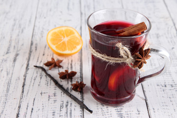 Mulled wine with lemon and spices on wooden background