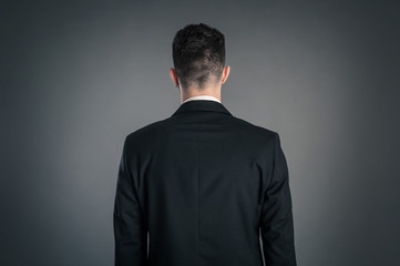 Portrait of a businessman back view isolated on dark background.