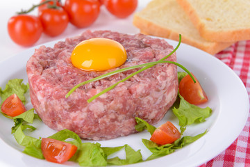 Delicious steak tartare with yolk on plate on table close-up