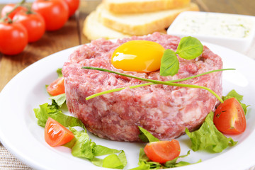 Delicious steak tartare with yolk on plate on table close-up