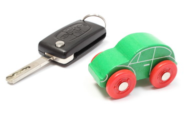 Old green toy car and vehicle key on white background