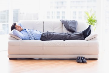 Tired businessman sleeping on a sofa - Powered by Adobe