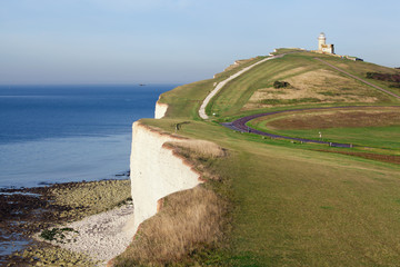 Lighthouse on a green hill overlooking the sea