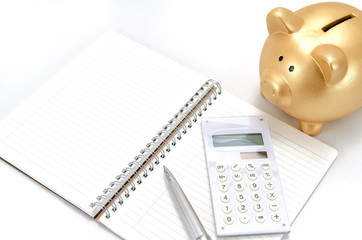 金色の豚の貯金箱と電卓とノート
