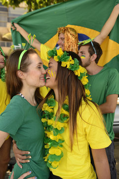 Brazilian girlfriends soccer fans almost kissing each other.