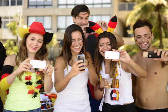 Group of happy German soccer fans holding smartphones