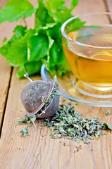 Obraz na płótnie Canvas Herbata ziołowa z melisy w kubek z sitkiem na pokładzie