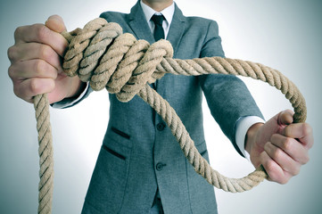 man in suit holding a rope with a hangmans noose