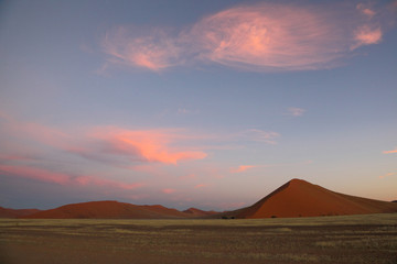 Fototapeta na wymiar Puffy Pink Clouds over Red sand dunes