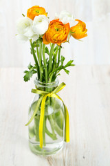 bouquet of white and orange buttercups on wooden table