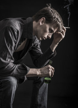 Depressed man thinking over his problems with smoking cigarette