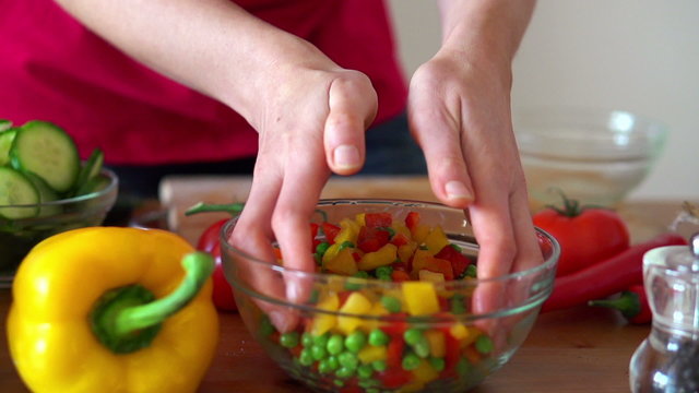 Female hands mixing vegetable salad in bowl