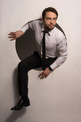 Businessman climbing out of a circular hole