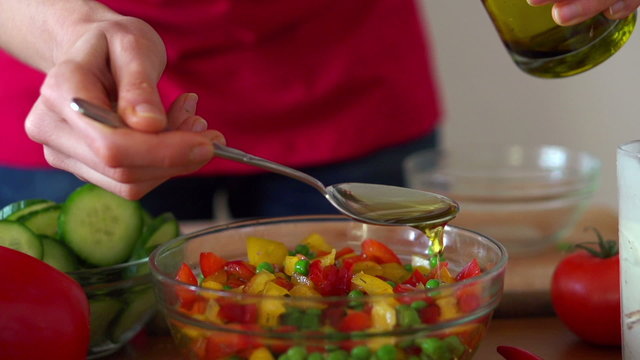 Pouring olive oil on fresh salad in bowl, super slow motion,