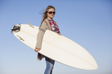Tenage girl in the beach with her surfboard
