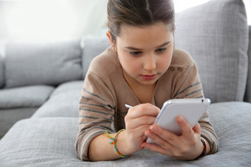 Little girl playing with smartphone at home
