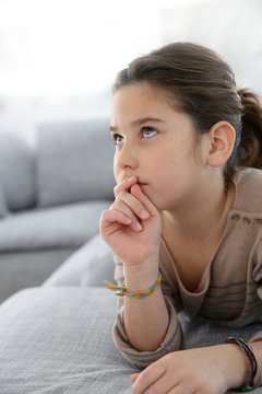 Young girl laying on couch with thoughtful look