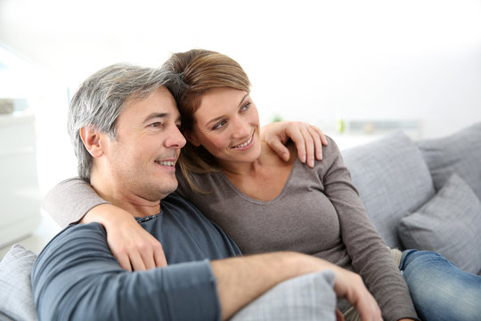 Middle-aged couple relaxing on sofa at home