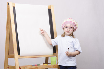 Девочка художник в очках рисует на мольберте
