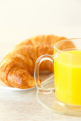 A croissant next to a mug of juice
