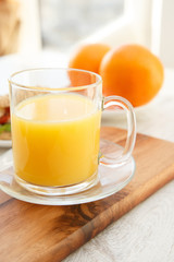 Cutting board with oranges and a cup of juice