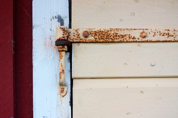 Detail of rusted hinge on wooden door