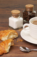 Croissants and crumbs near a cup of coffee
