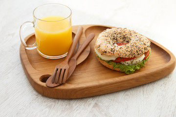 A bun sandwich and juice on a wooden plate
