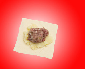 dough with meat on a red background